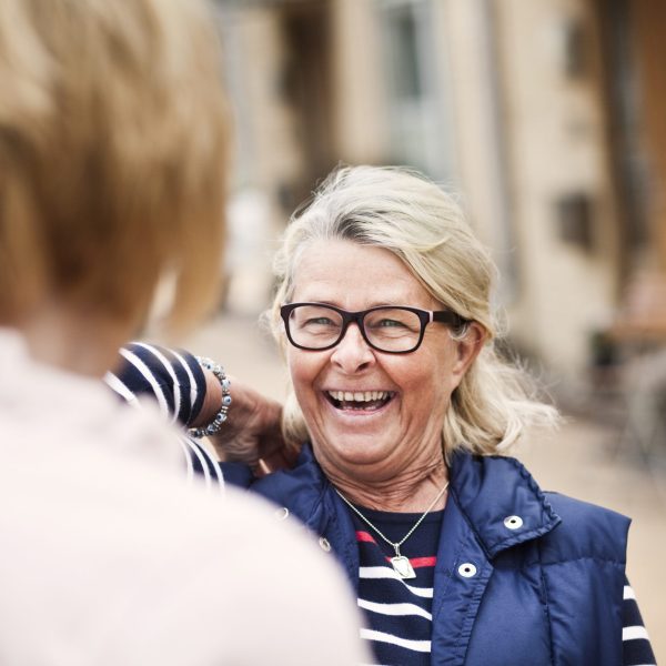Cheerful senior woman looking at female friend in city