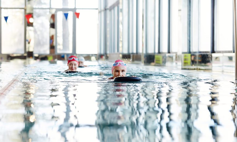 Swimming with supplies Active woman in swimwear swimming after black rubber ring while holding it by both hands